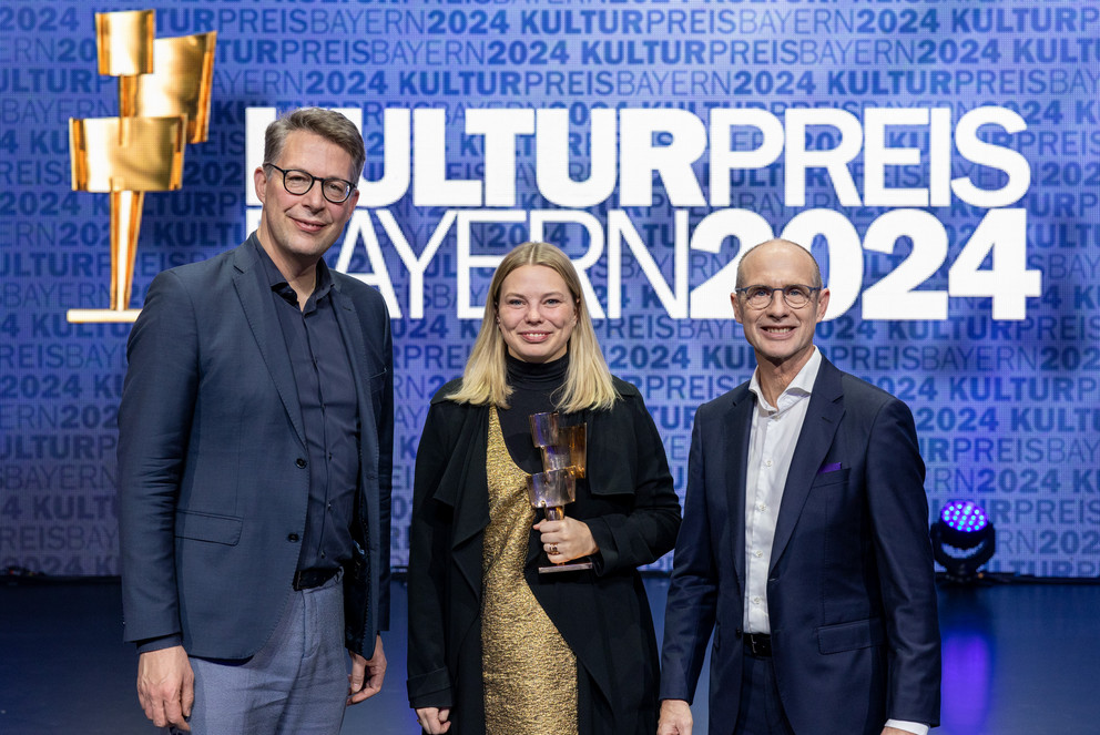 Preisträgerin Dr. Johanna Zimmermann steht neben Minister Markus Blume (l.) und Bayernwerk-Chef Dr. Egon Leo Westphal (r.).